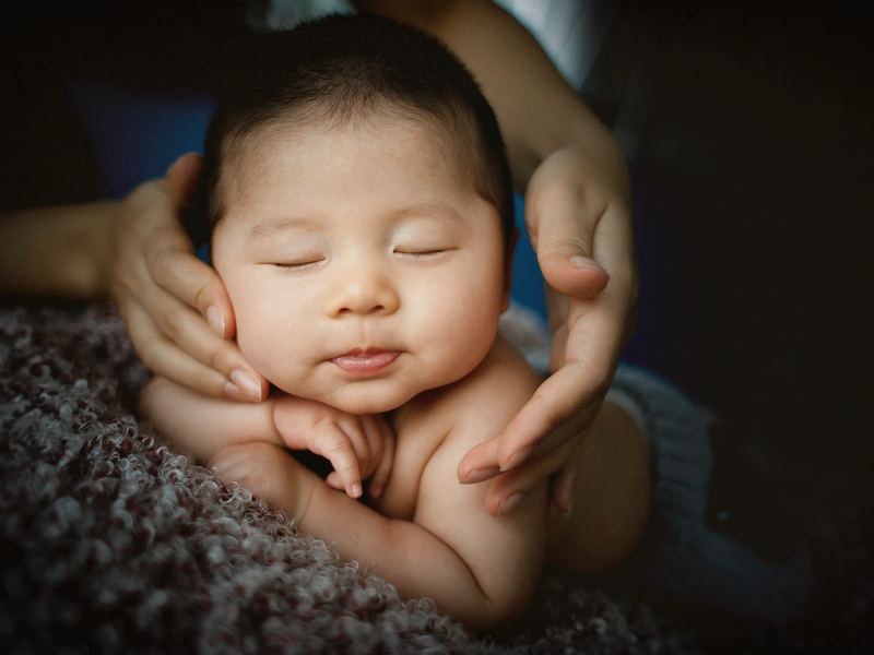 Un nouveau-né endormi, tenu dans les mains d'un adulte