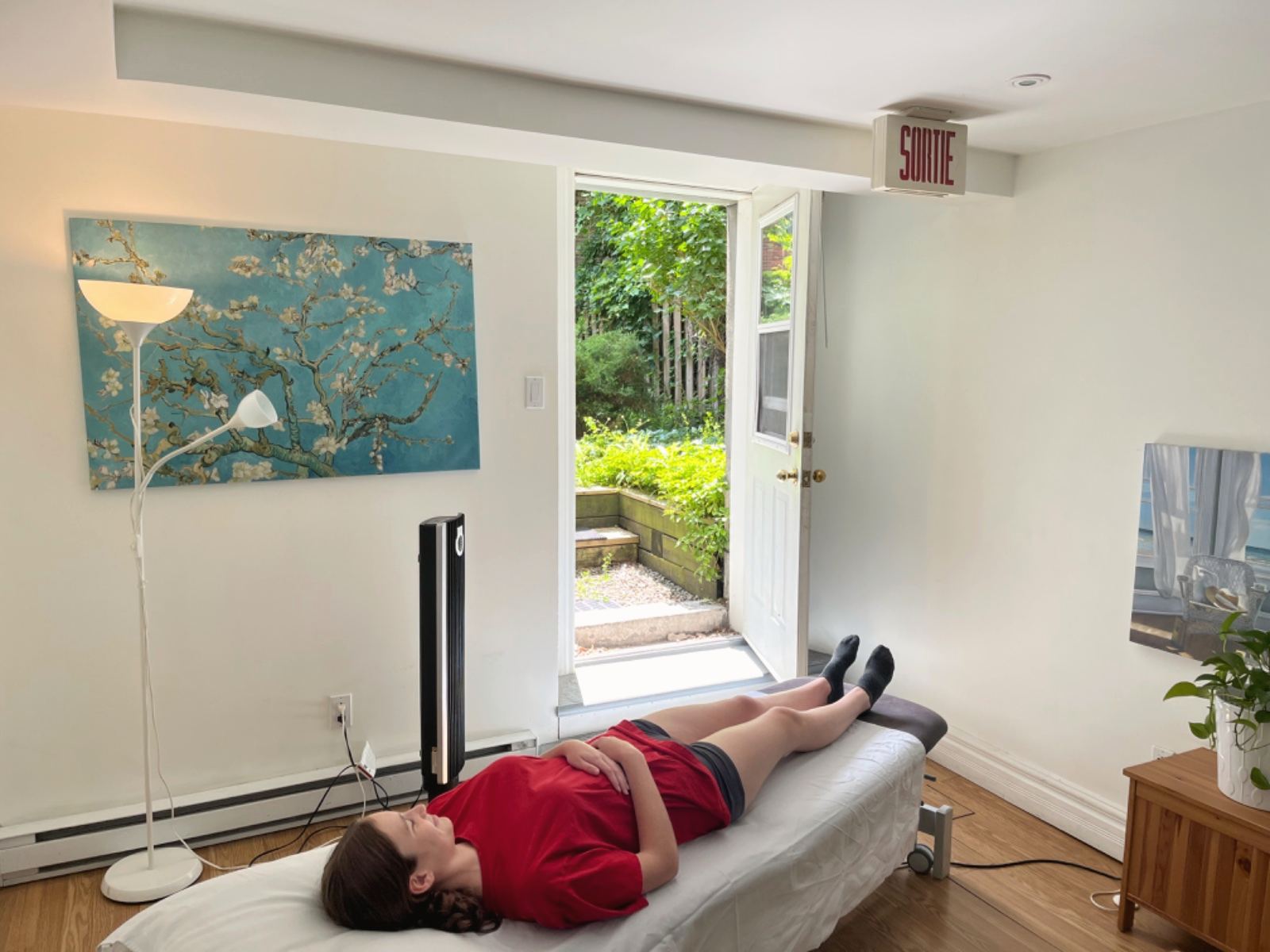 A person lying on the treatment table, the door open onto the garden