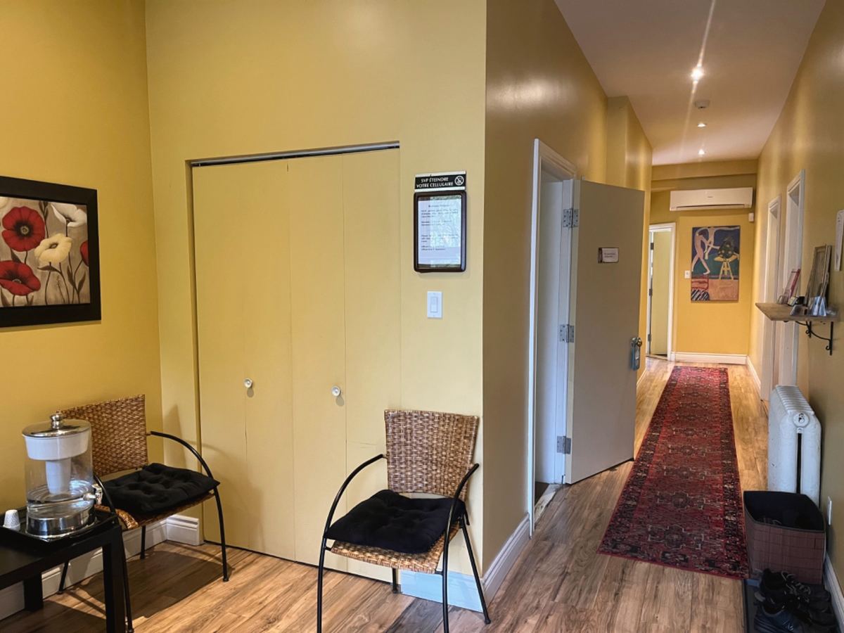 The clinic's waiting room, yellow walls, two rattan chairs, and the corridor with its long red carpet